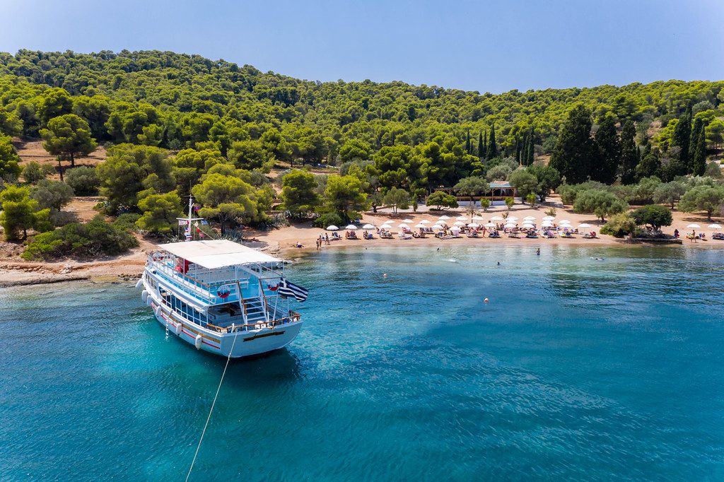 Aerial view of a greek island ferry in the blue ocean, in front of tourists at Zogeria Beach