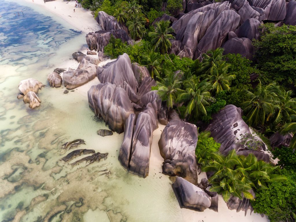 Aerial View shows rock formation of granite stones with palm trees at Anse Source d'Argent Beach on the tropical Island La Digue, Seychelles
