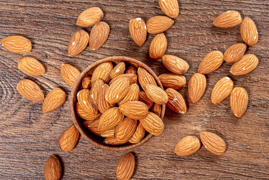 Almond nuts in wooden bowl on brown wooden background. Top view (Flip 2019)