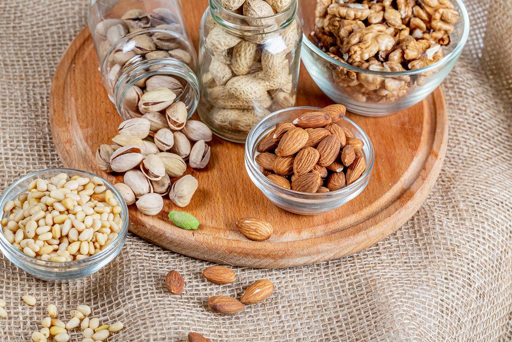 Almonds, pistachios, pine nuts and walnuts on a wooden kitchen board with burlap