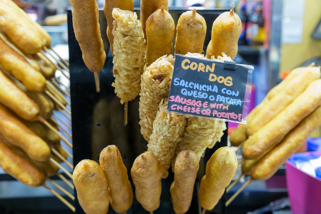Amerikanische Corn Dogs mit Käse und Kartoffeln, wird in der Markthalle Mercat de la Boqueria am Placa de Sant Josep in Barcelona, Spanien, verkauft
