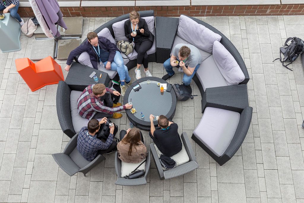 Ansicht von oben auf Menschen auf der runden Terrassen-Couch der Veranda des AXA-Gebäudes, Teilnehmer des Barcamp OMWest 2019 in Köln