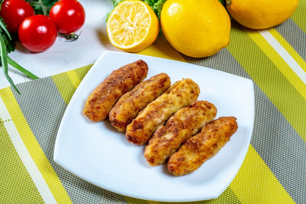 Appetizing dietary fish sticks on a green tablecloth with lemons