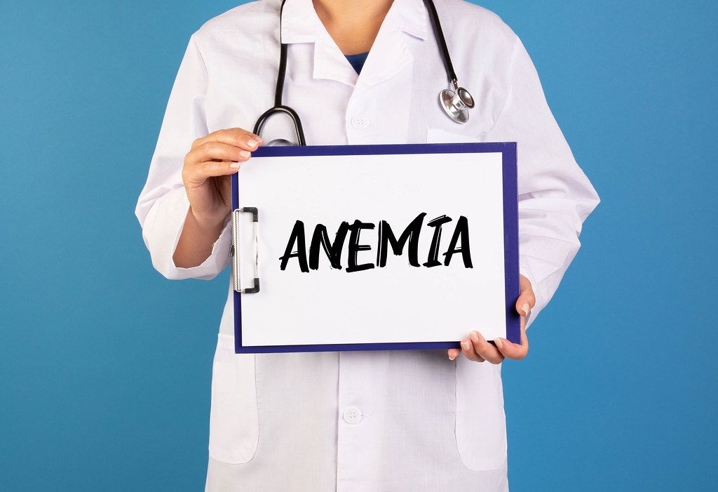 Arzt hält ein Schild mit der Schrift 'Anemia' im blauen Hintergrund