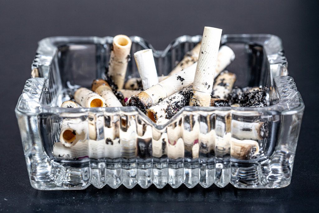 Ashtray with cigarette butts on a black background