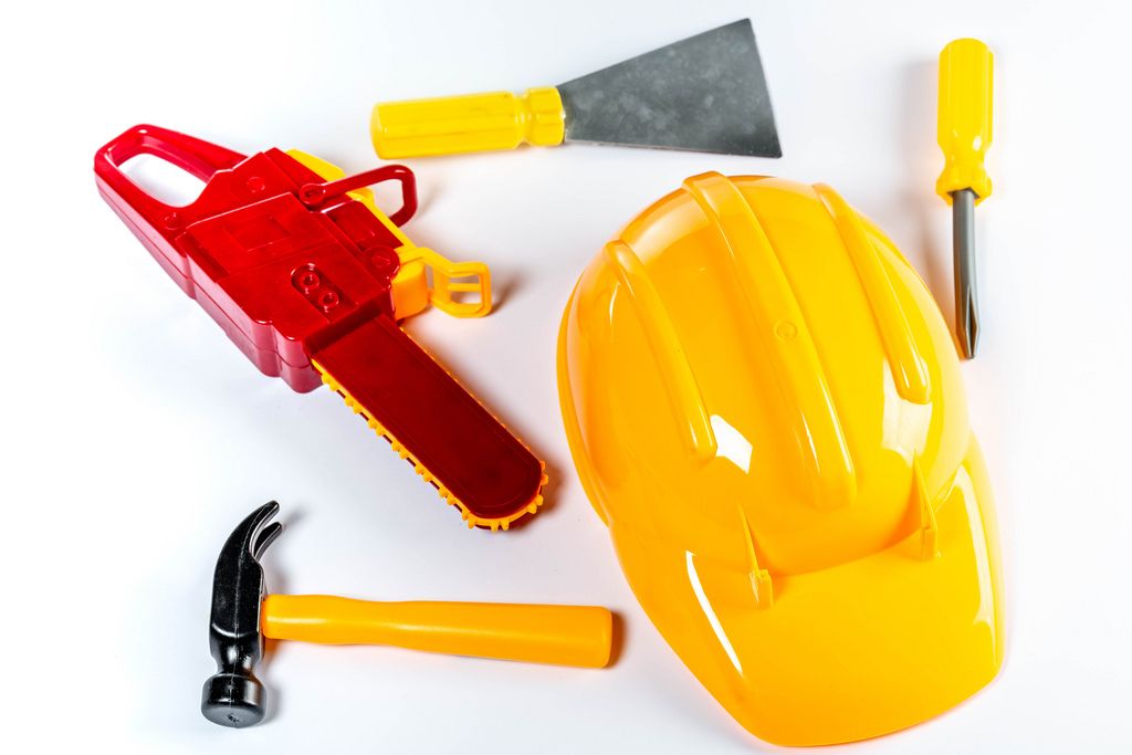 Assorted plastic toy tools and yellow helmet over white background (Flip 2019)