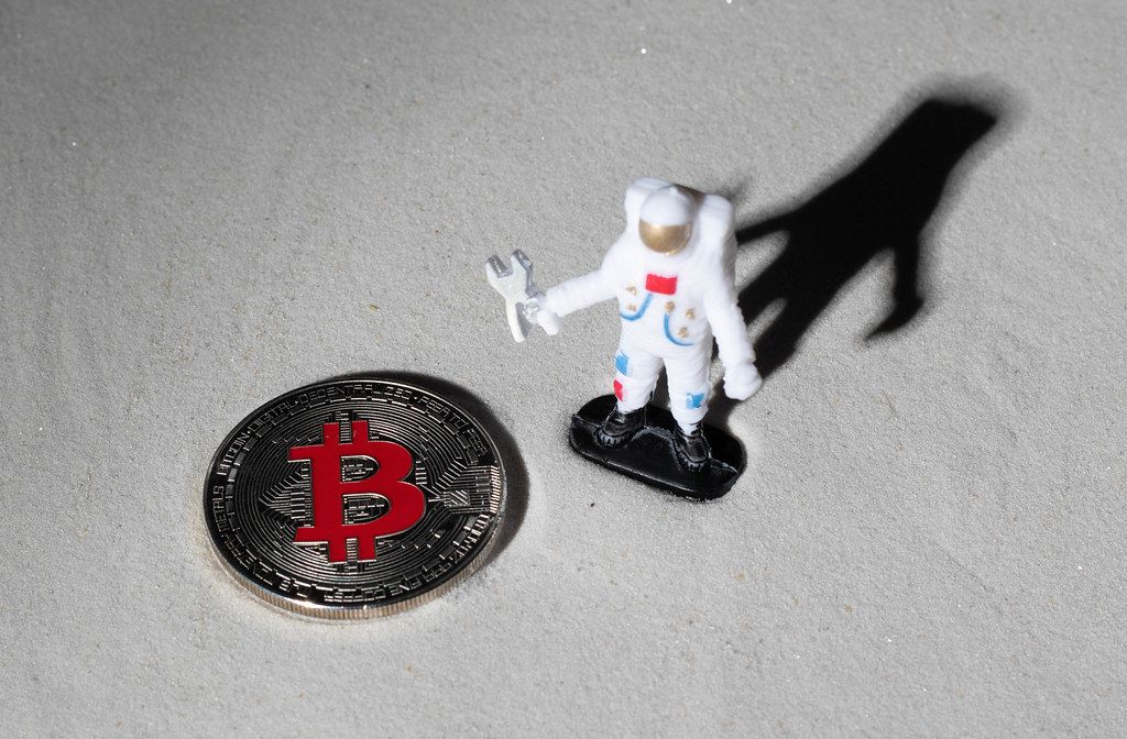 Astronaut und silberne Bitcoin-Münze auf dem Mond