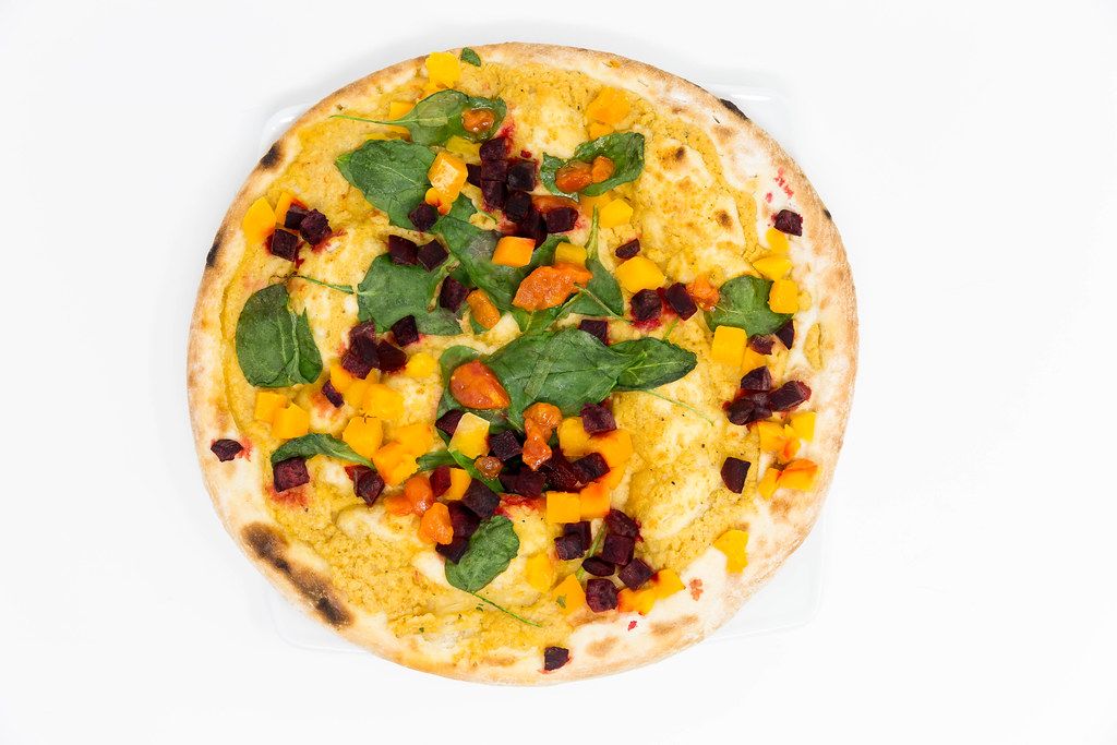 Aufnahme von oben der Yoga-Pizza Vegan von Followfood mit Bio-Dinkelboden, ausgewähltem Bio-Gemüse, Hummussauce und ayurvedischen Gewürzen von Herbaria