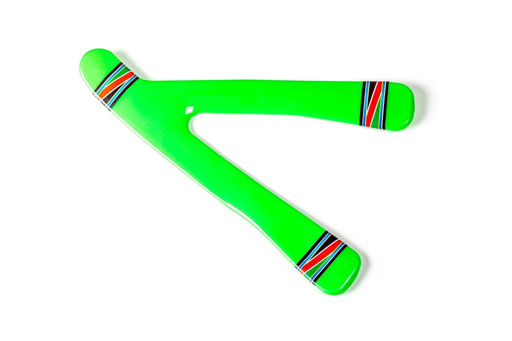 Aufnahme von oben. Grüner Bumerang aus Kunststoff auf weißem Hintergrund