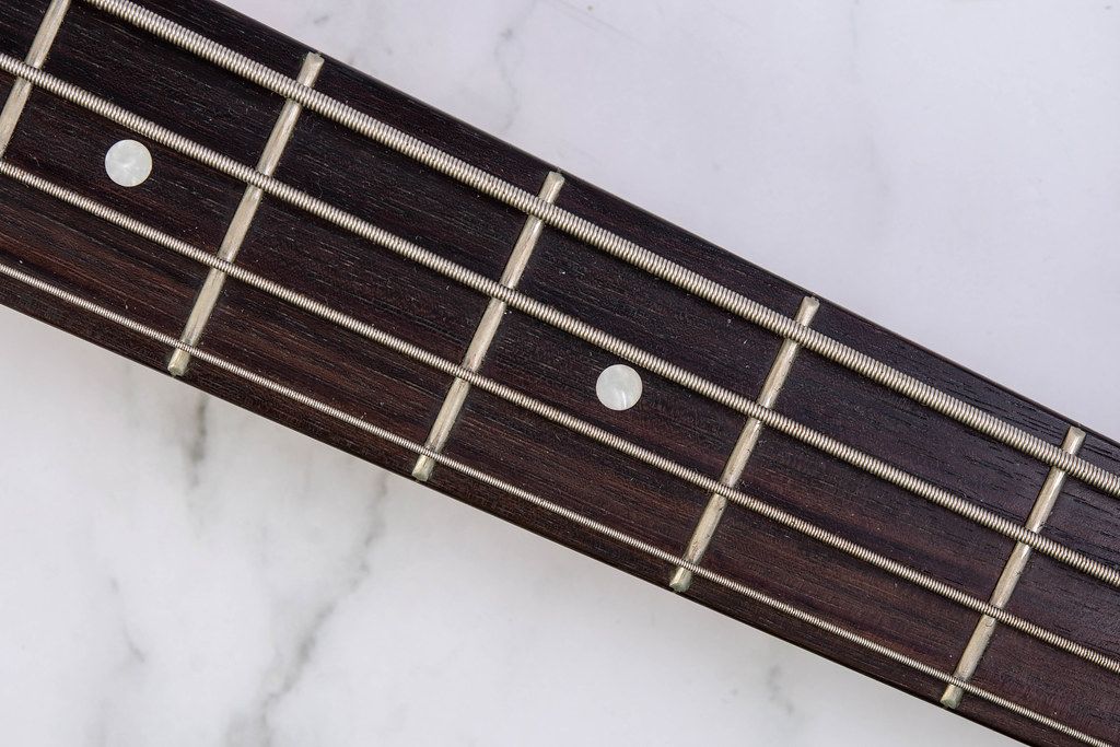 Bass Guitar Neck with Strings above marble background