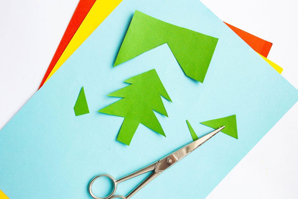 Basteln - Eine Schere mit buntem Papier - Weihnachtsbaum-Auschnitt