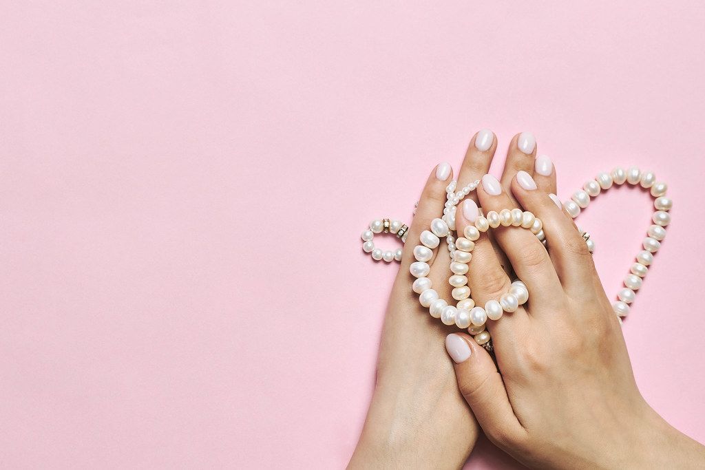 Beautiful female hands with manicure holding pearls