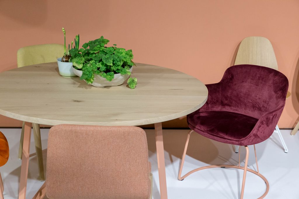 Bequeme, mit weichem Stoff bezogene Stühle stehen um runden Holztisch