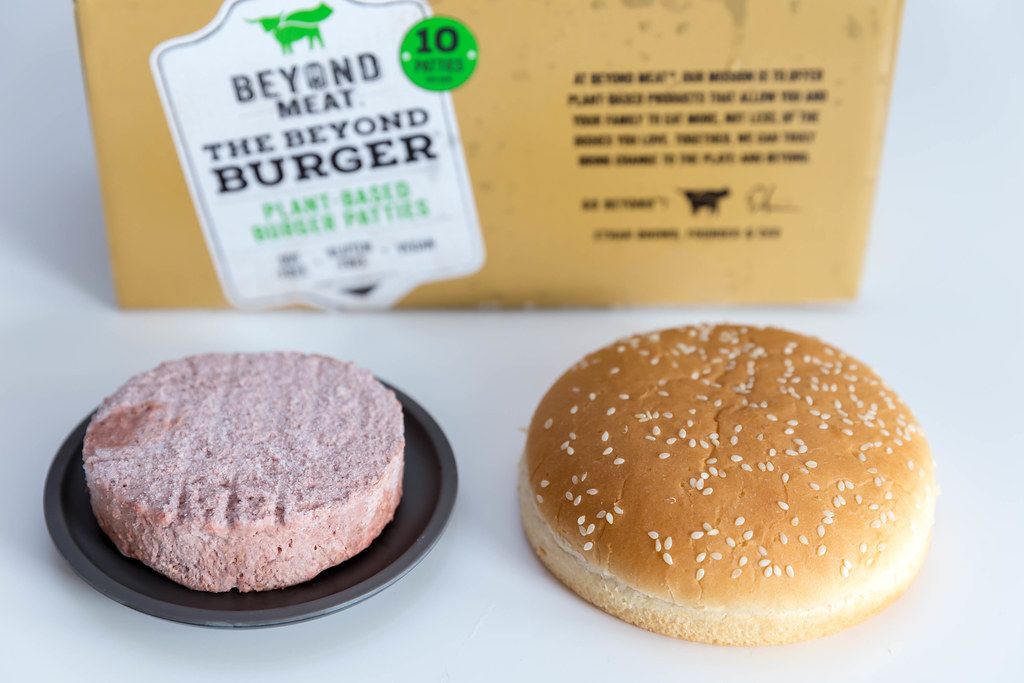Beyond Meat vegan gluten-free burger patty on black plate with burger bun next to it