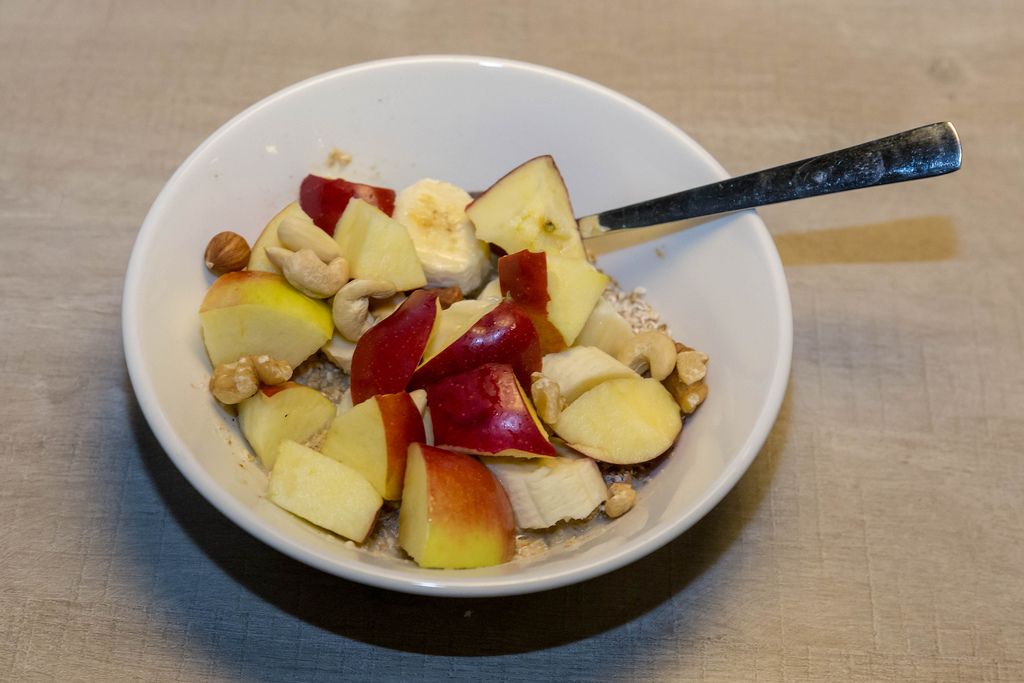 Biologisches Vanille-Chia Porridge mit Äpfeln, Bananen und verschiedenen Nüssen in weißer Schale