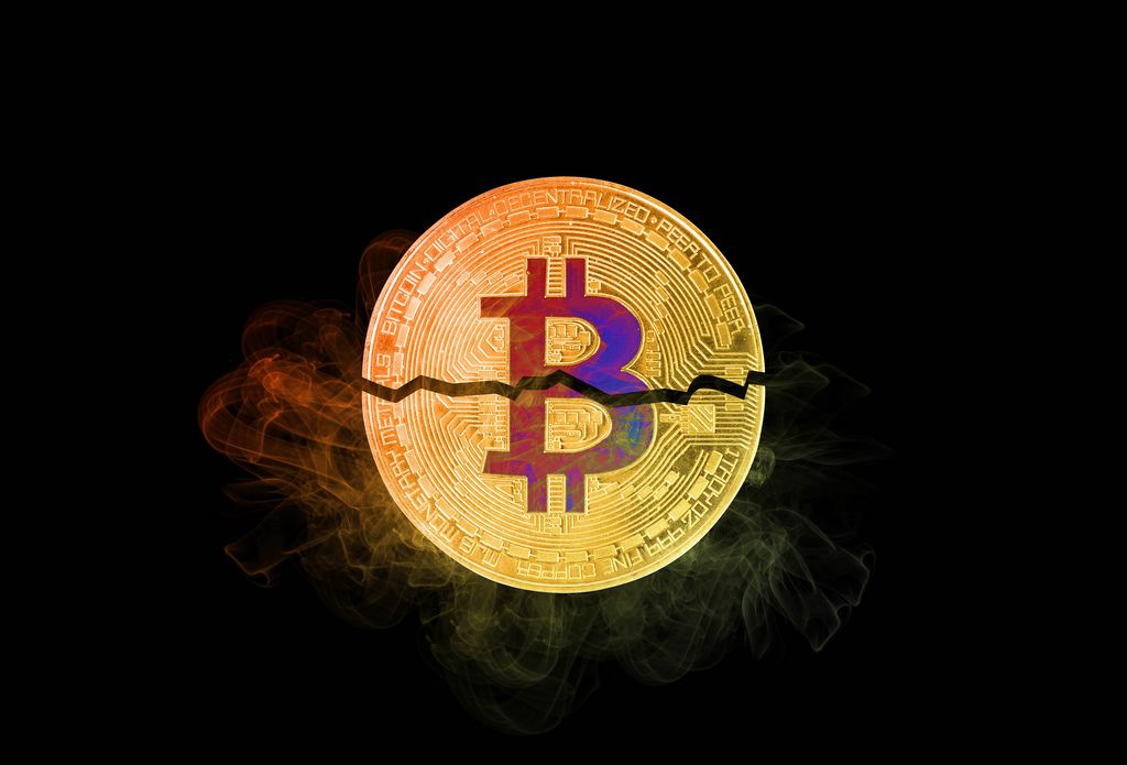 Bitcoin broken in half with colorful smoke on black background