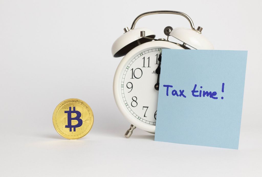 Bitcoin Steuerberechnung - Ein Wecker und ein Bitcoin auf weißem Hintergrund