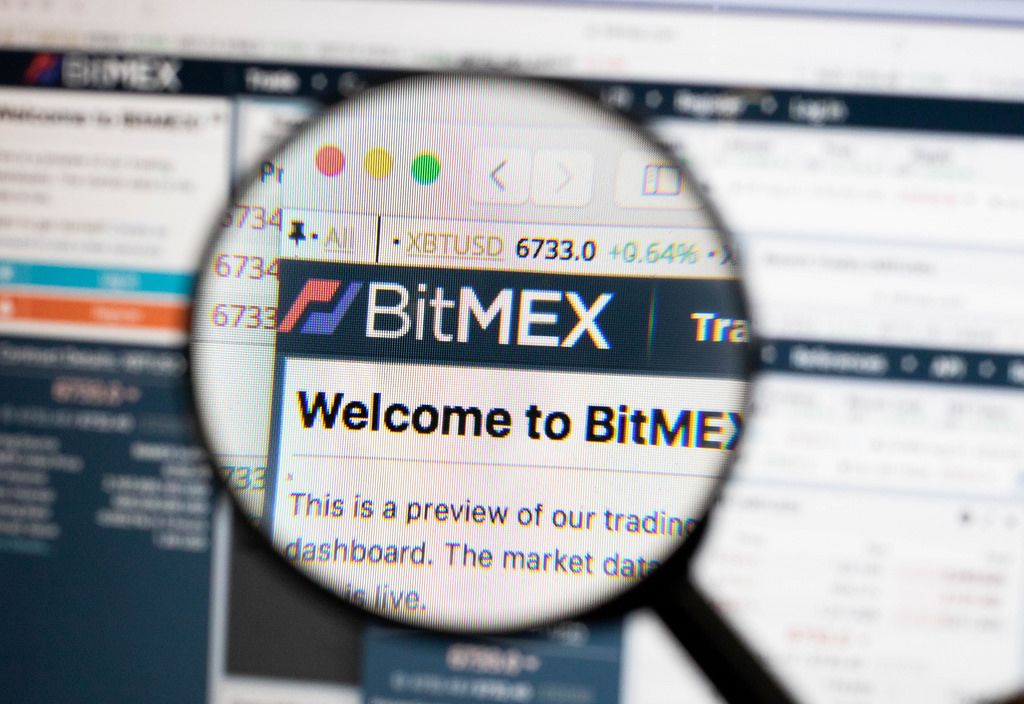 Bitmex-Logo am PC-Monitor, durch eine Lupe fotografiert
