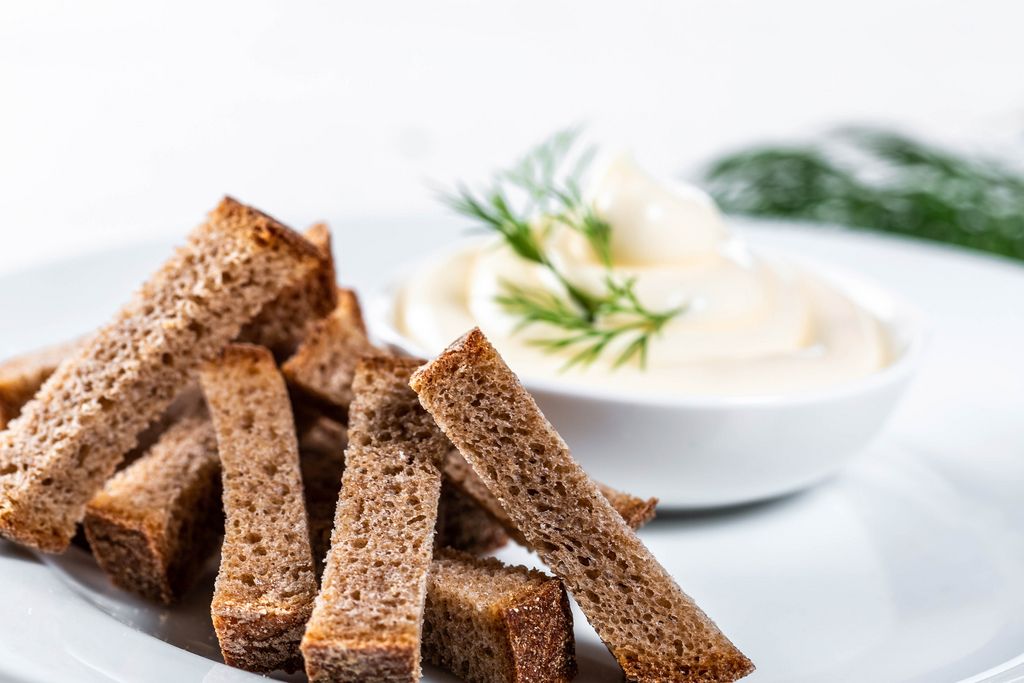 Black bread crackers with white sauce and dill