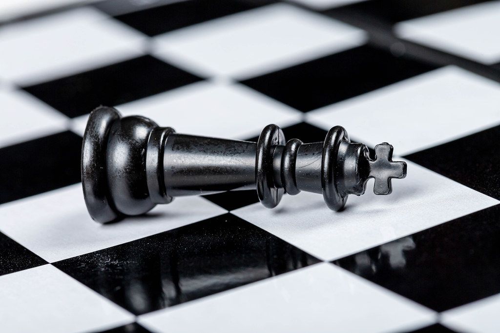 Black king chess piece lies on a chessboard. The concept of losing, losing and failing (Flip 2019)