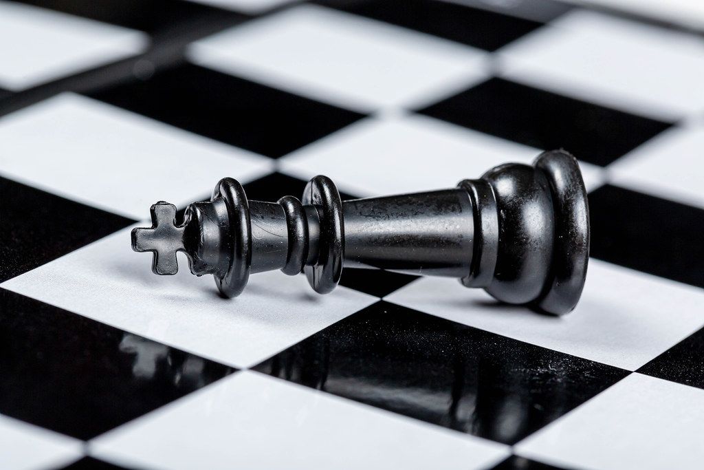 Black king chess piece lies on a chessboard. The concept of losing, losing and failing
