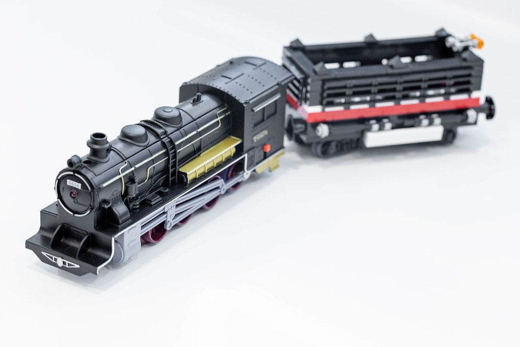Black toy locomotive with a wagon on a white background