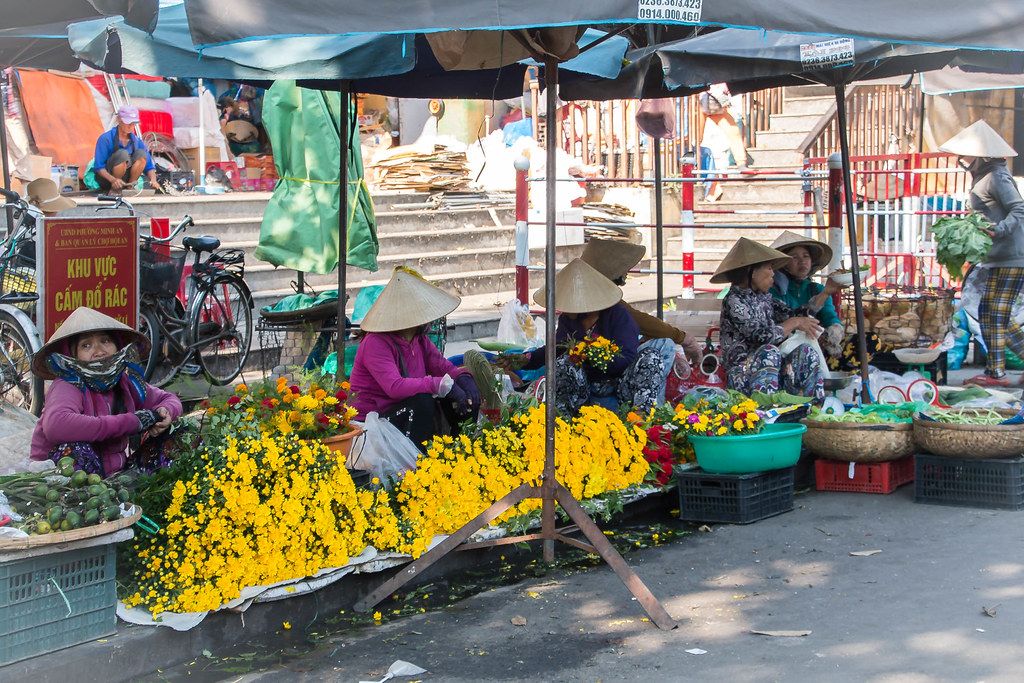 Blumenmarkt in Vietnam und einheimische Frauen mit Kegel-Bambushut