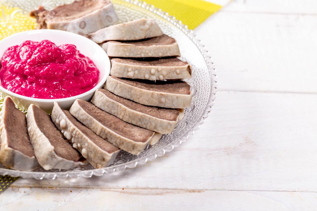 Boiled tongue with horseradish sauce on white wooden table