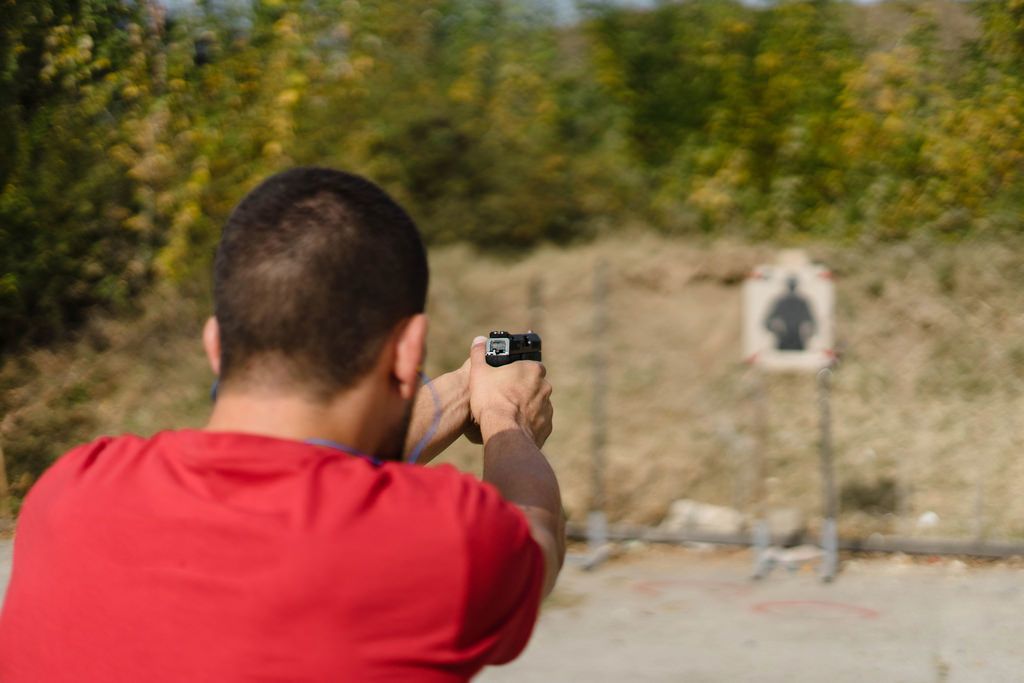 Bokeh eines Schützen der mit einer Pistole auf eine Zielscheieb schießt