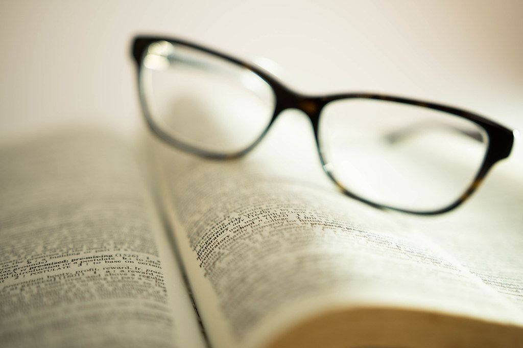 Bokeh Photo of Reading Glasses laying on a page of an open Book