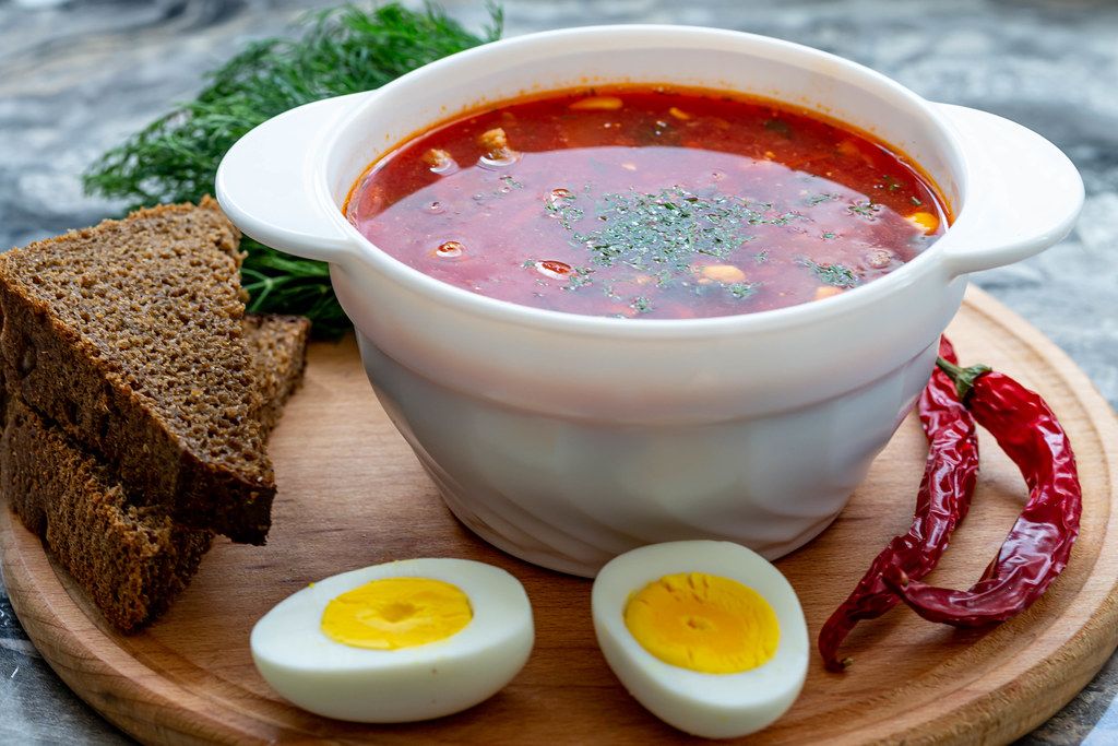 Bowl of beetroot soup borsch with egg, pepper and slices of black bread (Flip 2019)