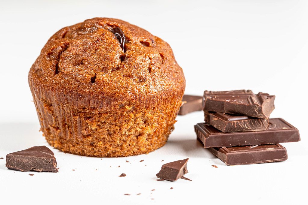 Brauner Muffin mit Schokoladenstücken vor weißem Hintergrund - Creative ...