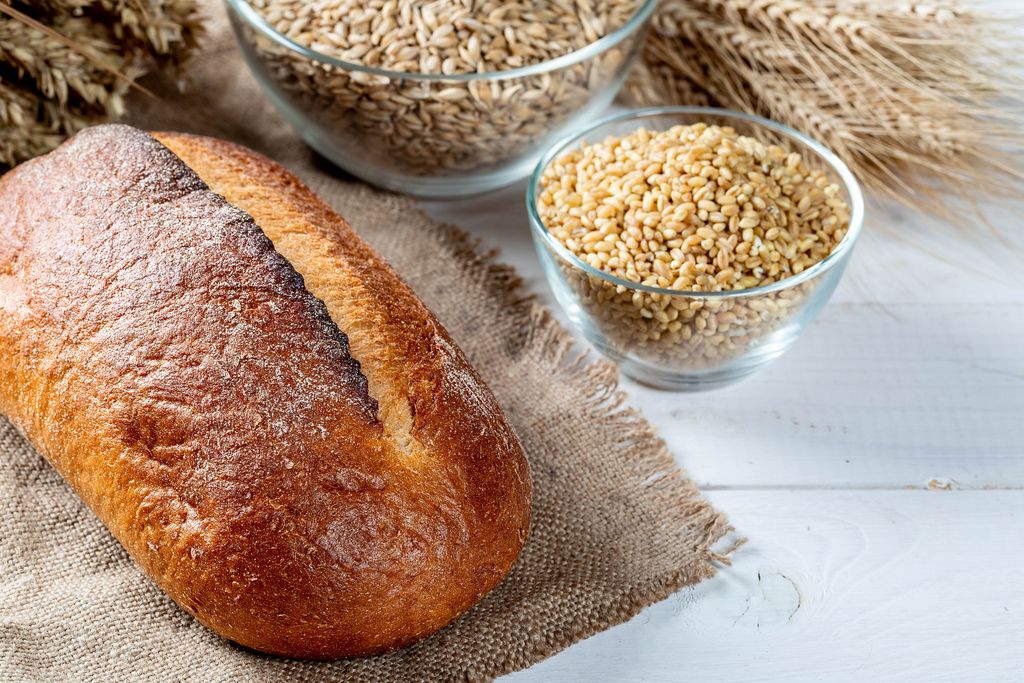 Bread with wheat and spikelets on a white wooden table
