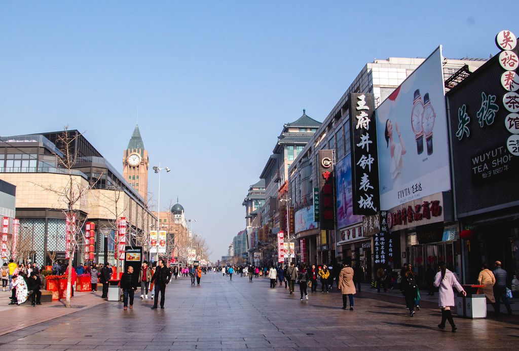 Breite Einkaufsstraße mit  Geschäften und Kirchturm in Beijing, China