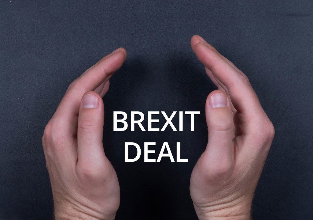 Brexit Deal Text mit Männerhänden vor schwarzem Hintergrund