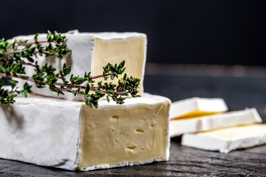 Brie cheese with fresh thyme on black background (Flip 2019)