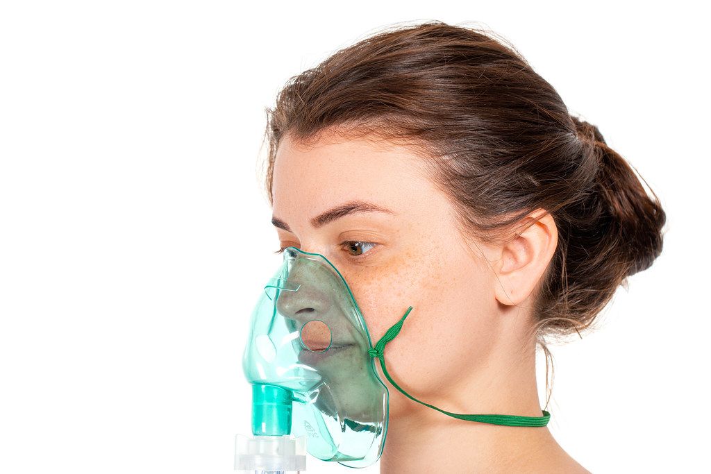 Brunette woman with nebulizer mask on his face