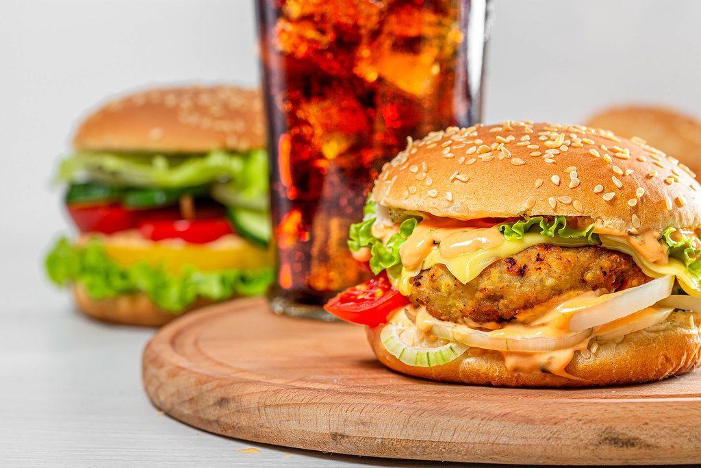 Burger with cutlet, cheese and vegetables with a glass of Coca Cola (Flip 2019)