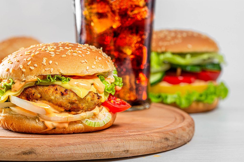 Burger with cutlet, cheese and vegetables with a glass of Coca Cola