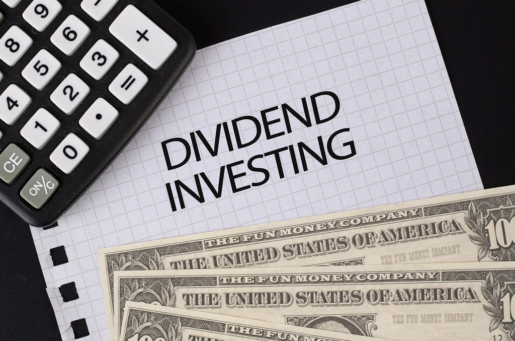 Calculator, money and Dividend Investing text on black table