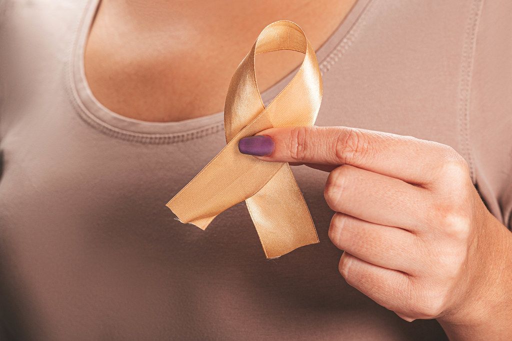 Children Healthcare and World cancer day concept. Gold ribbon in a female hand