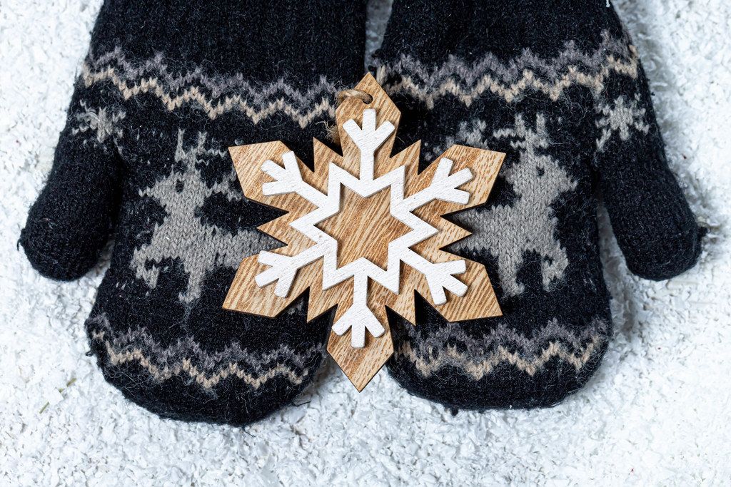 Children's hands in mittens hold a wooden snowflake on a background of snow. Winter concept (Flip 2019)