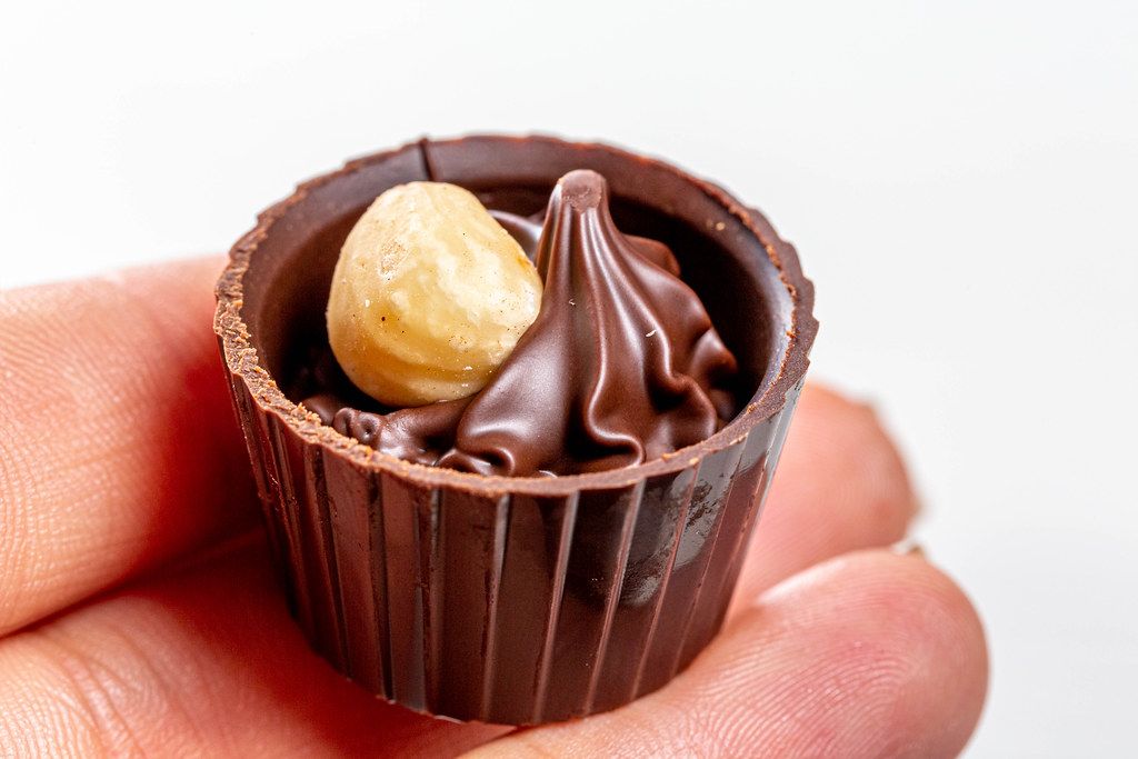 Chocolate candy with hazelnuts in a woman's hand