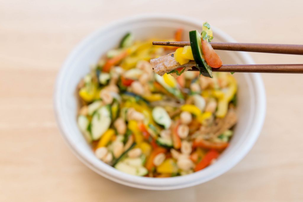 Chopsticks with a portion of food over vegan dish of vegetables on wooden table