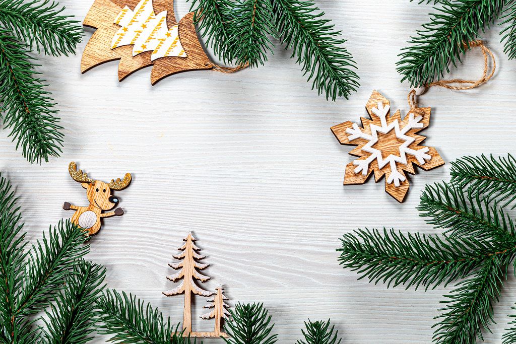 Christmas frame from wooden decorations and Christmas tree branches on a white wooden background (Flip 2019)