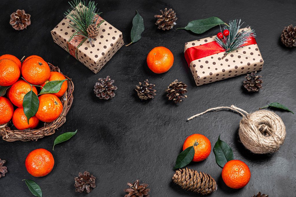Christmas gifts with tangerines and cones on a black background. The view from the top (Flip 2019)