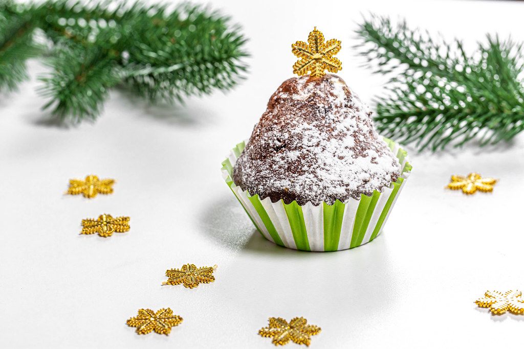 Christmas muffin with Christmas tree branches and snowflakes on a white background