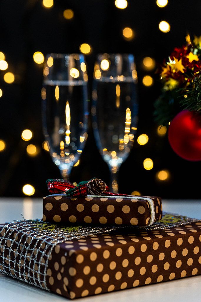 Christmas presents and glasses of champagne on bokeh background