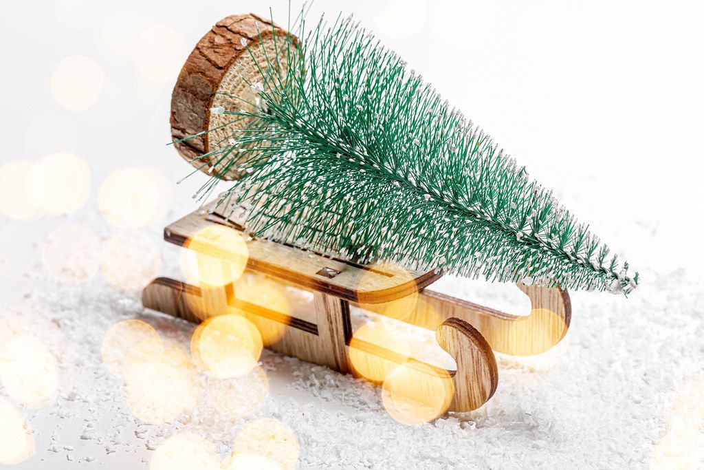 Christmas tree on a wooden sleigh on the background of snow. Christmas background with bokeh