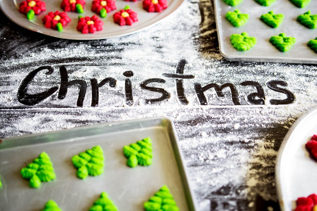 CHRISTMAS written on flour with christmas cookie baking sheets around